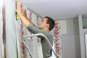 Young apprentice learning how to put wallpaper up on wall