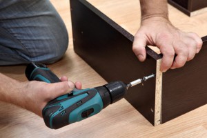 Assembling furniture from chipboard, Woodworker screwing Chipboard screws using a cordless screwdriver.